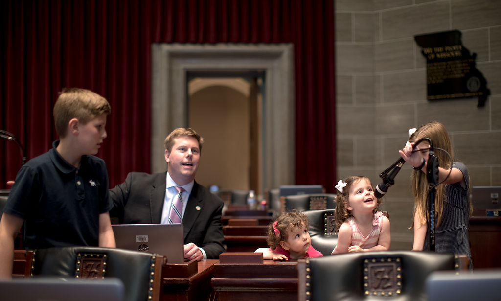 Owen Plocher, 11, and Rep. Dean Plocher watch as children use a microphone